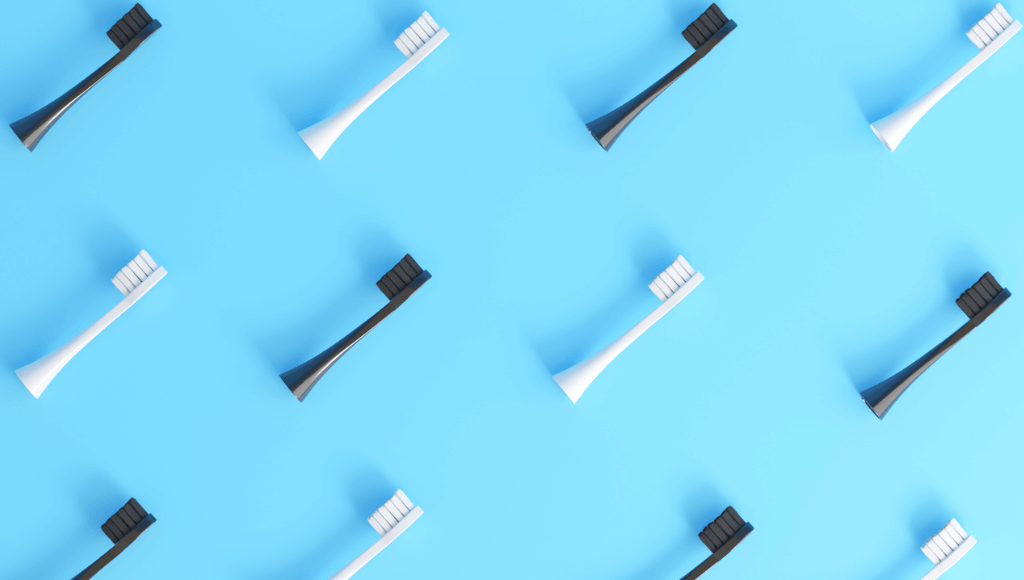 Têtes de brosses à dents noires et blanches placées en quinconce sur un fond turquoise Immagine
