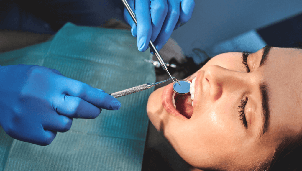 Mains avec gants en caoutchouc bleu examinant les gencives d'une femme chez le dentiste Afbeelding